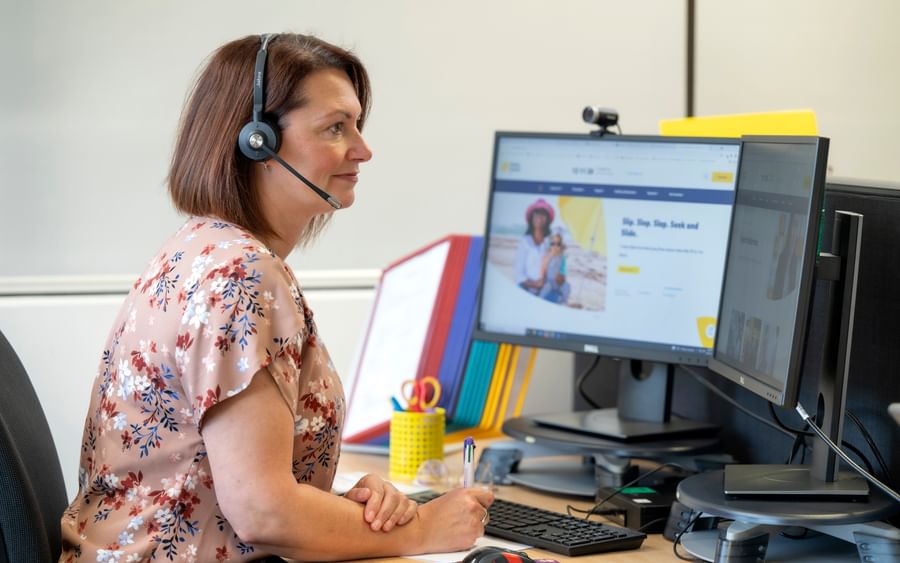 woman wearing a headset looking at a computer screen